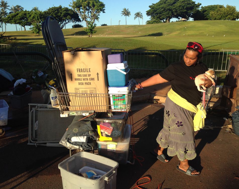 Loveleen Mori, 27, a homeless woman living in a large encampment in the Kakaako neighborhood of Honolulu, holds her dog as she tries to figure out where to bring her belongings as city officials start to sweep the camp, Thursday, Oct. 8, 2015.
